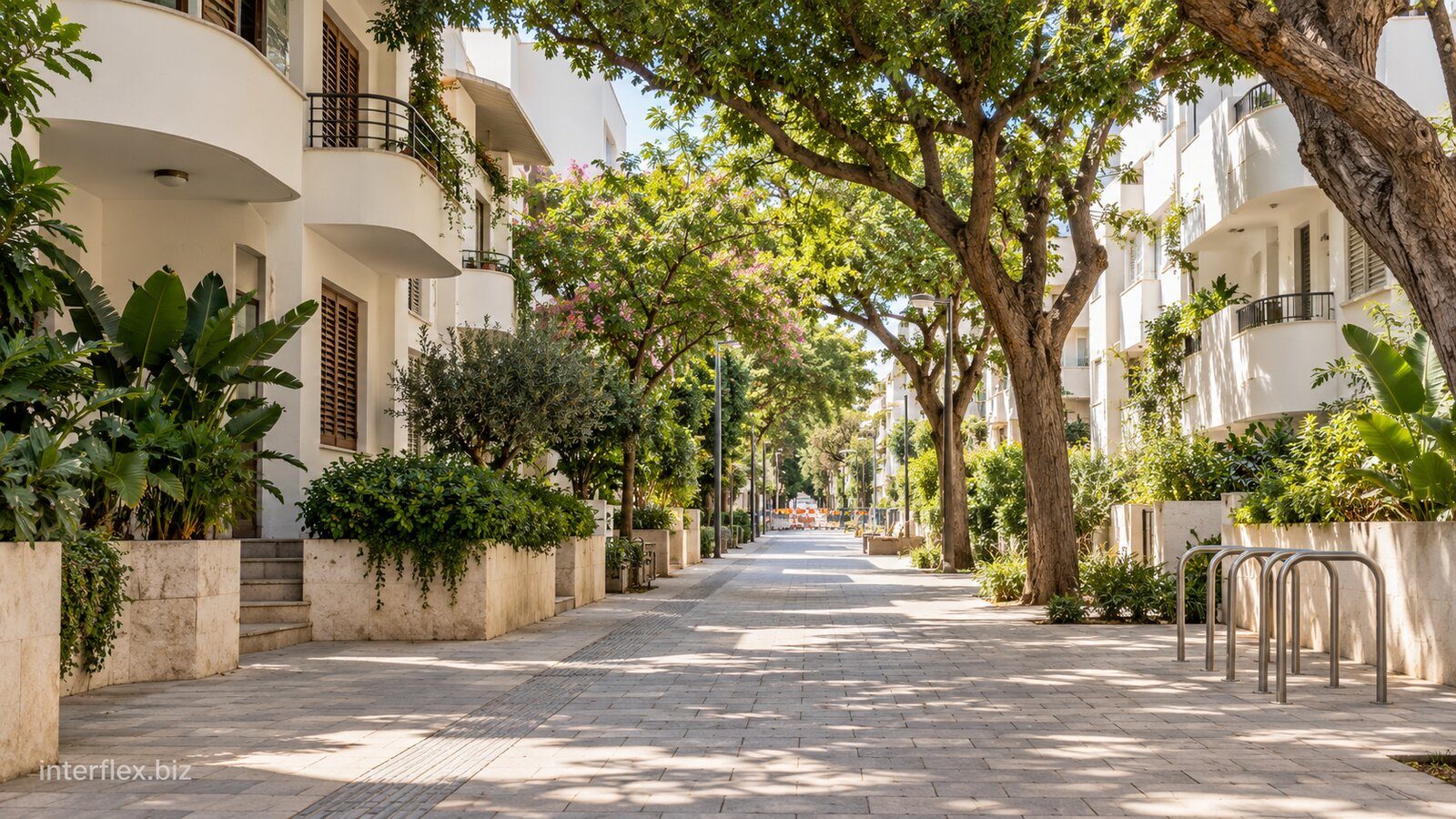 שביל עירוני מוצל בין בניינים לבנים ומתקן אופניים ריק, תמונת המחשה